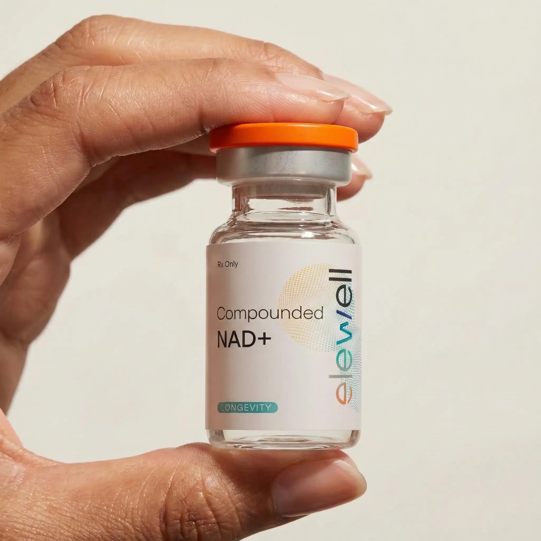 Hand holding a small glass bottle labeled 'elewell' with an orange cap on a neutral background